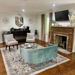 A luxurious, residential-style waiting room. It features a decorative fireplace, a light blue velvet sofa, a patterned area rug on hardwood floors, and elegant furniture, creating a relaxing, non-clinical environment